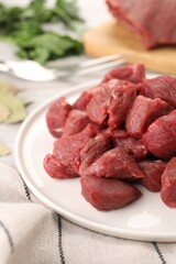 Plate with pieces of raw beef meat on table, closeup