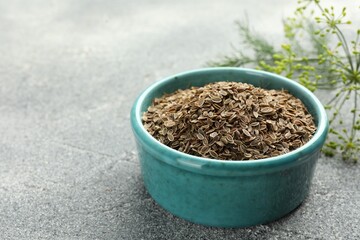 Bowl of dry seeds and fresh dill on grey table, closeup. Space for text