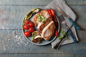 Delicious grilled meat and vegetables served on wooden table, flat lay