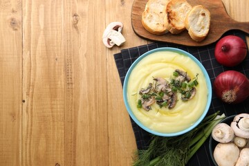 Bowl of tasty cream soup with mushrooms, green onions and dill on wooden table, flat lay. Space for text