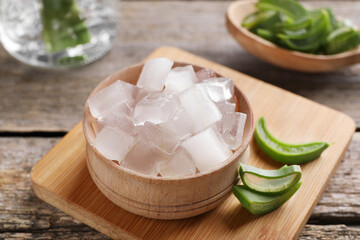 Aloe vera gel and slices of plant on wooden table, closeup
