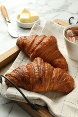 Tray with tasty croissants served on white marble table, closeup