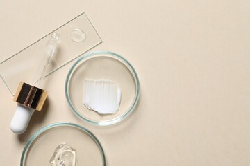 Pipette, cosmetic serum and petri dishes with samples on beige background, flat lay. Space for text