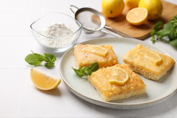 Tasty lemon bars and mint on white table