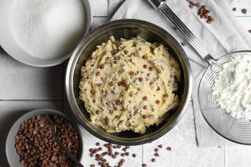 Chocolate chip cookie dough in bowl and ingredients on table, flat lay
