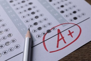 Fototapeta premium School grade. Answer sheet with red letter A, plus symbol and pencil on wooden table, closeup