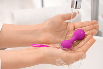 Woman washing anal plug over sink, closeup - obrazy, fototapety, plakaty