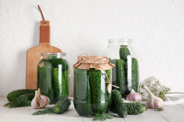 Jars with canned and fresh cucumbers on table
