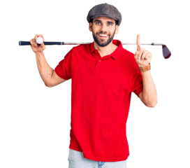Young handsome man with beard playing golf holding club and ball surprised with an idea or question pointing finger with happy face, number one