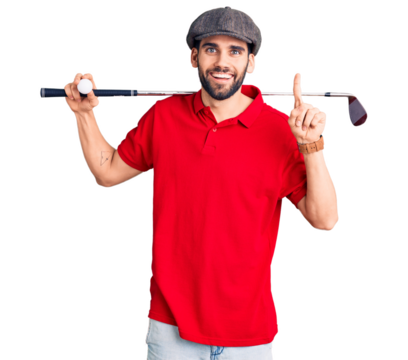Young handsome man with beard playing golf holding club and ball surprised with an idea or question pointing finger with happy face, number one