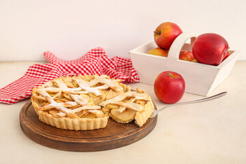 Wooden board with delicious apple pie and basket of fresh fruits on white background