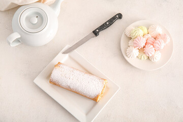 Plates with sweet sponge cake roll, tea pot and meringue on white background