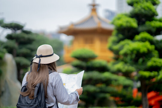 Asian tourist, cute woman with long hair are traveling in Hong Kong along with map and her camera with fun on her holiday, A temple in Hong Kong, concept travel, Nan Lian garden, Chinese classical. 