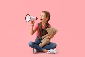 Foto op Canvas Little girl with megaphone and teddy bear sitting on pink background © Pixel-Shot