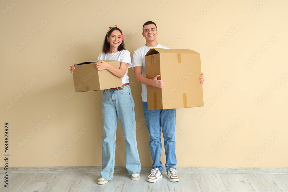 Wall mural happy young couple with moving boxes near beige wall