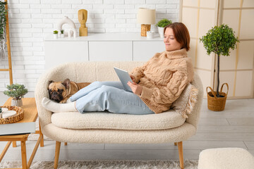 Young woman with cute dog using tablet computer at home