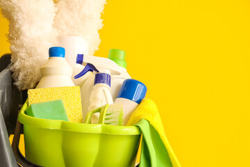 Trolley with cleaning supplies near yellow wall, closeup