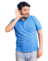 Young hispanic man wearing casual clothes smiling with hand over ear listening an hearing to rumor or gossip. deafness concept.