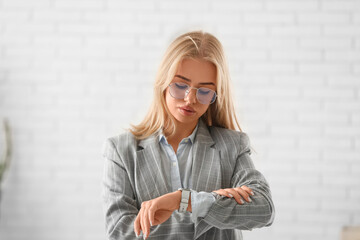 Young businesswoman with wrist watch trying to meet deadline in office. Time management concept