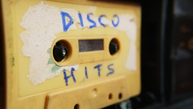 Old music audio player. Rotating tape on an old vintage cassette with inscription. Retro disco music concept.