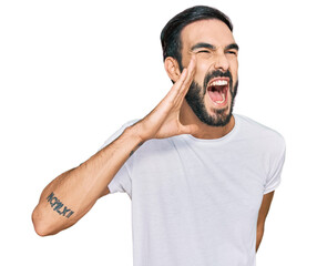 Young hispanic man wearing casual white t shirt shouting and screaming loud to side with hand on...