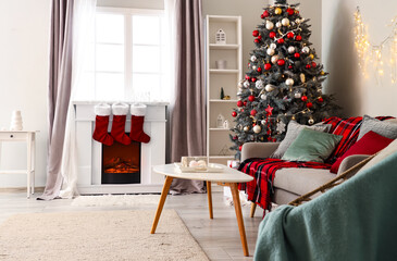 Interior of living room with sofa, Christmas tree and fireplace