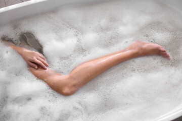 Fototapeta premium Woman taking bath in tub with foam, top view