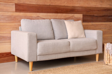 Grey sofa with pillow near wooden wall in room