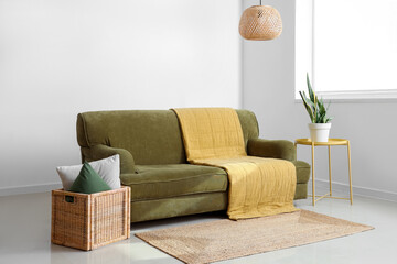 Interior of light living room with green sofa, table and basket