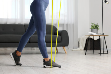 Woman doing exercise with fitness elastic band at home, closeup