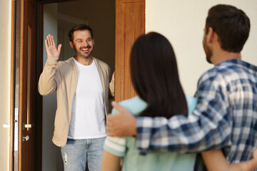 Fototapeta premium Friendly relationship with neighbours. Young couple visiting happy man