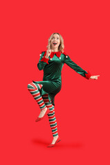 Happy young woman dressed as elf on red background
