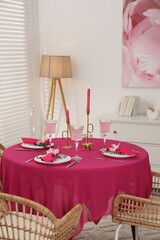 Beautiful table setting with green branches and burning candles in dining room