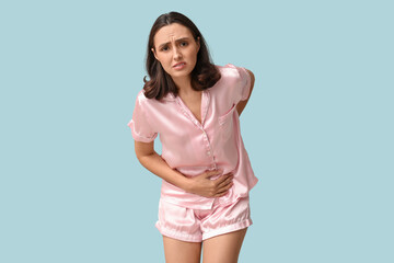 Beautiful young woman suffering from menstrual cramps on blue background