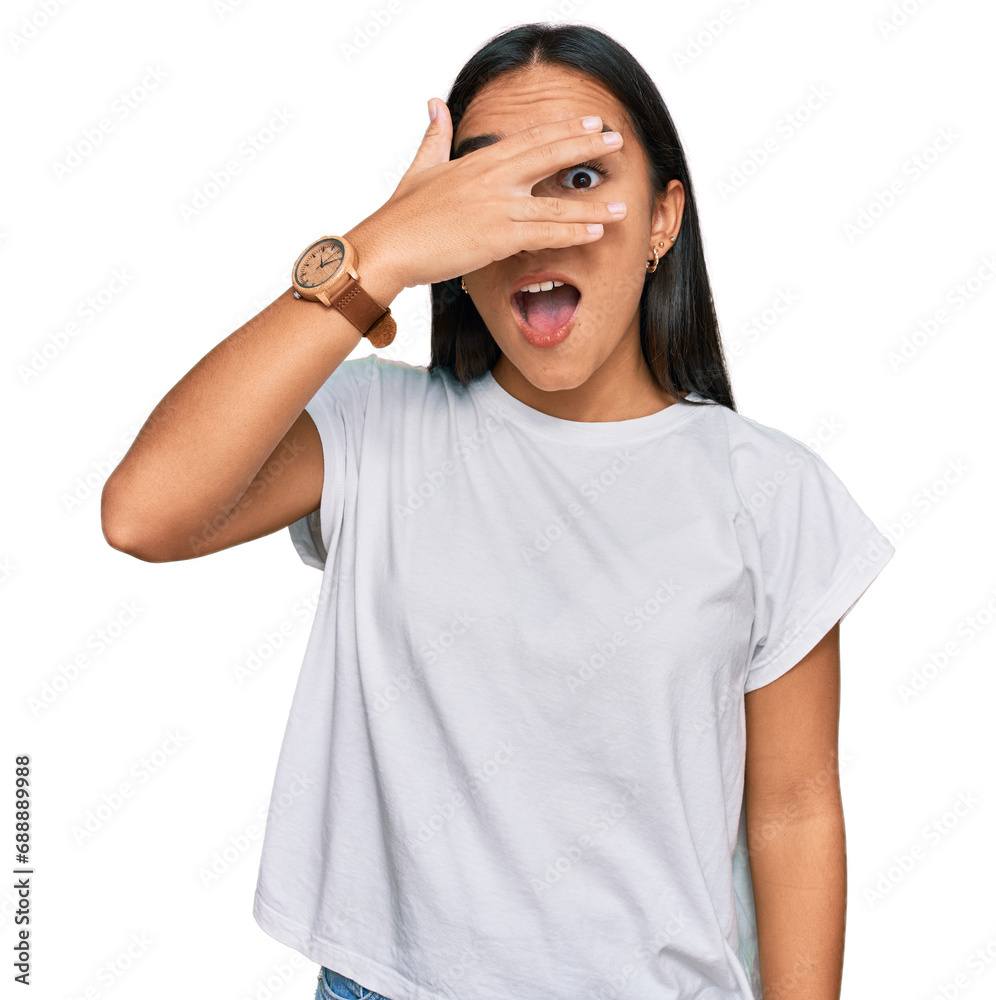 Poster Young asian woman wearing casual white t shirt peeking in shock covering face and eyes with hand, looking through fingers with embarrassed expression.