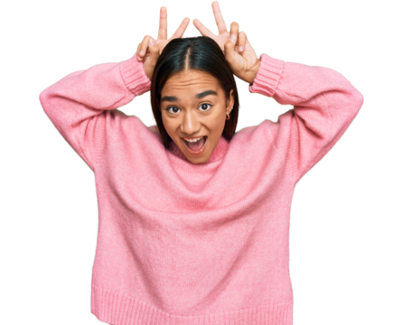 Young asian woman wearing casual winter sweater posing funny and crazy with fingers on head as bunny ears, smiling cheerful
