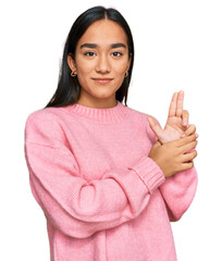 Young asian woman wearing casual winter sweater holding symbolic gun with hand gesture, playing killing shooting weapons, angry face