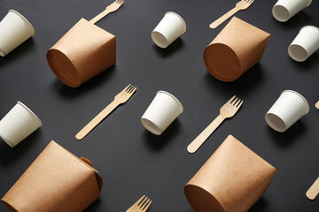 Takeaway paper cups, boxes and forks on black background