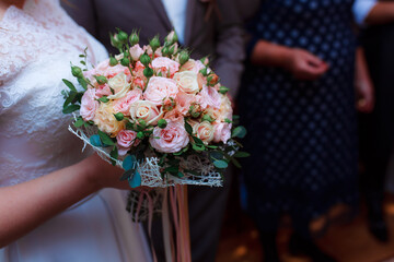 Delicate wedding bouquet in the hands of the bride at the ceremony. Hands of a newly-married couple...