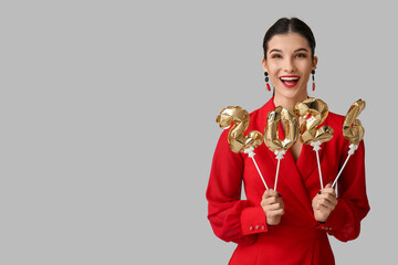 Beautiful young happy woman with figure 2024 made of balloons on grey background. Chinese New Year...