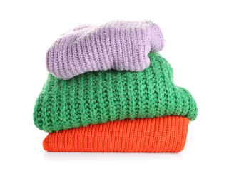 Stack of new different stylish sweaters on white background
