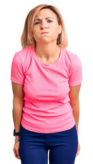 Fototapeta premium Young blonde woman wearing sportswear puffing cheeks with funny face. mouth inflated with air, crazy expression.