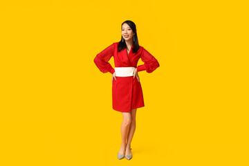 Beautiful young happy Asian woman on yellow background. Chinese New Year celebration