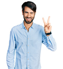 Hispanic man with blue eyes wearing business shirt smiling with happy face winking at the camera...