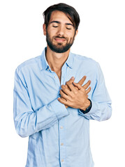 Hispanic man with blue eyes wearing business shirt smiling with hands on chest with closed eyes and grateful gesture on face. health concept.