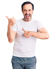 Middle age handsome man wearing casual t-shirt pointing to the back behind with hand and thumbs up,...