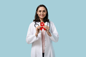 Female doctor with red ribbon on blue background. World AIDS Day concept