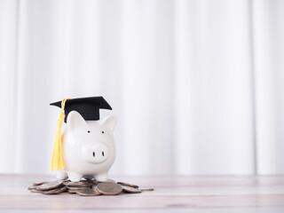Piggy bank with graduation hat on stack of coins. The concept of saving money for education,...