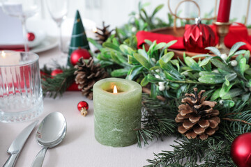 Burning candle with Christmas decorations on festive served table, closeup