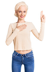 Young blonde woman wearing casual clothes smiling swearing with hand on chest and fingers up,...